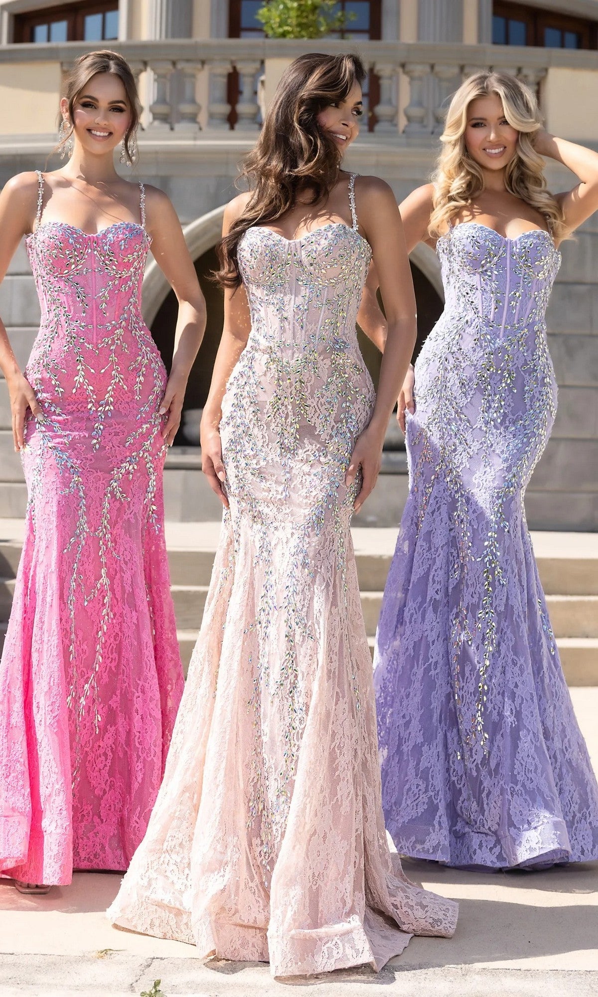Three women stand outdoors in fitted, floor-length Portia and Scarlett PS25150 prom dresses in Cinderella Pink AB with crystal beading. A stone building appears in the background.